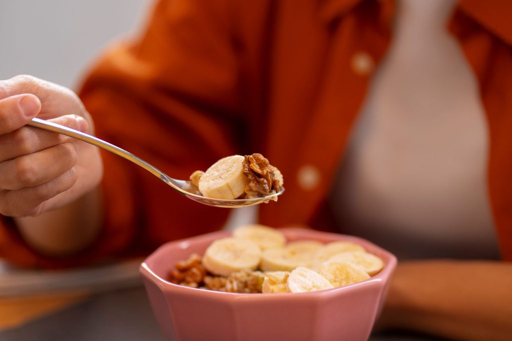 Adult holding a spoonful of soft food during a calm mealtime, showing safe eating and participation.