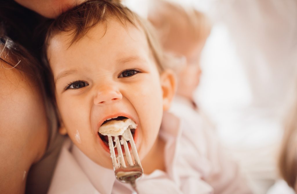 Child eating soft food during a calm mealtime, showing chewing and feeding participation.