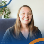 Professional headshot of Belinda Greig seated indoors with a plant behind.