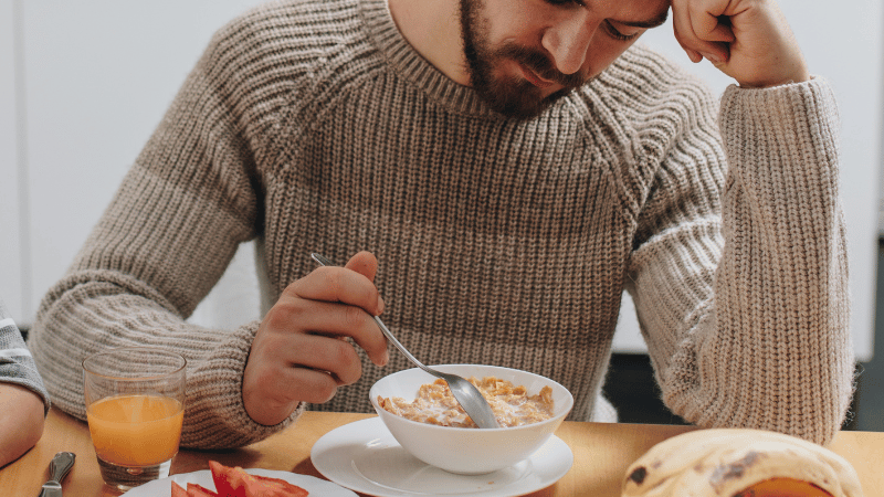Adult eating breakfast at a kitchen table, representing independent eating and everyday mealtime participation.