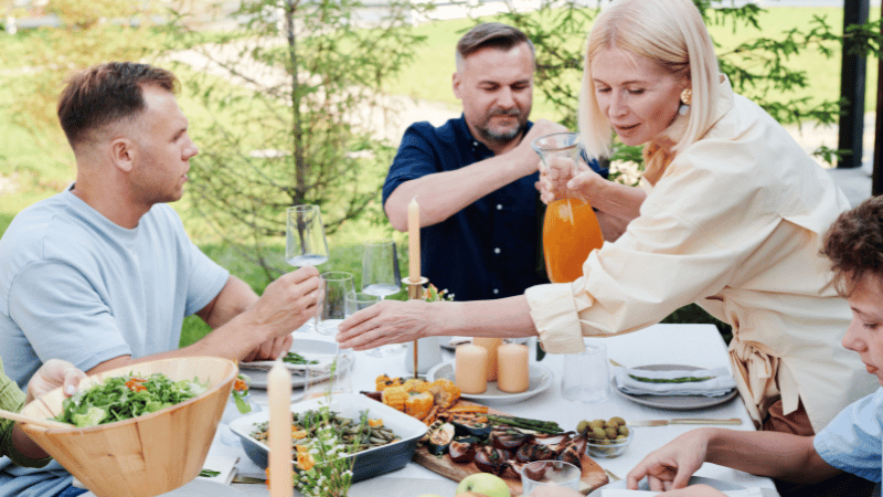 Adults sharing a meal at an outdoor table, representing social eating and mealtime participation.