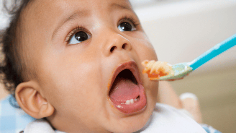 Young child being gently offered a spoonful of food, representing Thrive’s supportive, developmentally informed approach to infant feeding.