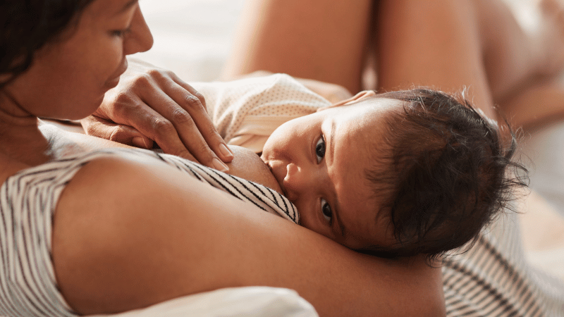 Adult breastfeeding an infant, representing nurturing, responsive feeding and early breastfeeding support.