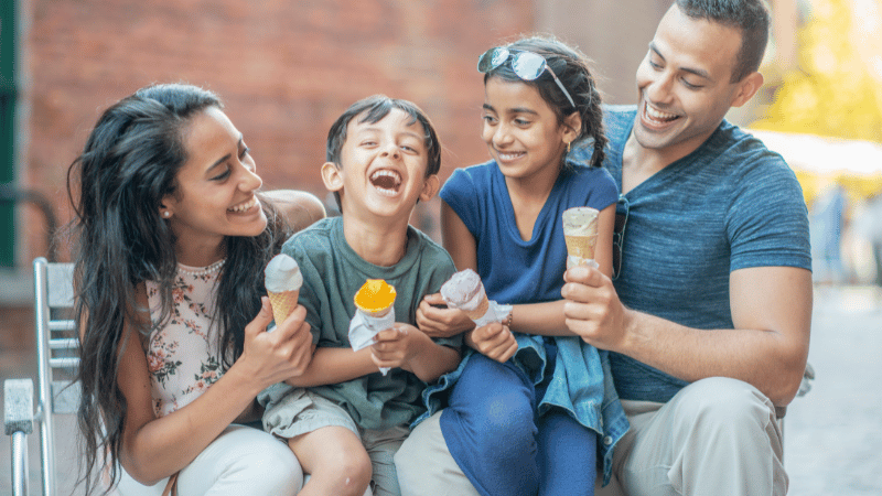 Adults and children sharing ice cream outdoors, representing family and community mealtime participation for NDIS participants.