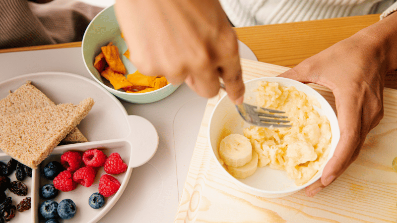 Person preparing food at a table, representing feeding routines and sensory‑based mealtime support for NDIS participants.