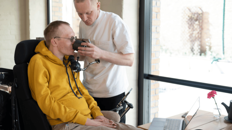 Person being supported to drink, representing mealtime training for NDIS participants.