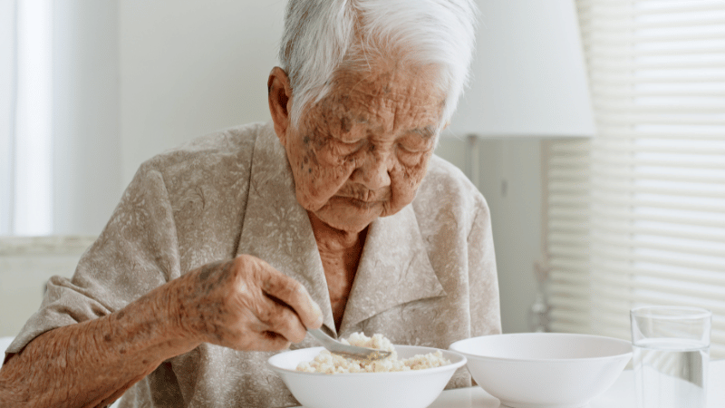 Older adult eating a meal at a table, representing independent eating and mealtime participation.
