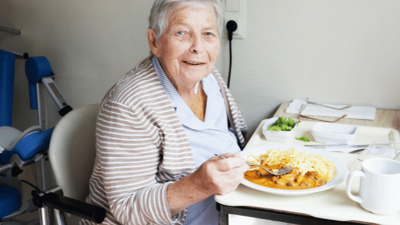 Older adult eating a meal in a care setting, representing mealtime participation in supported environments.