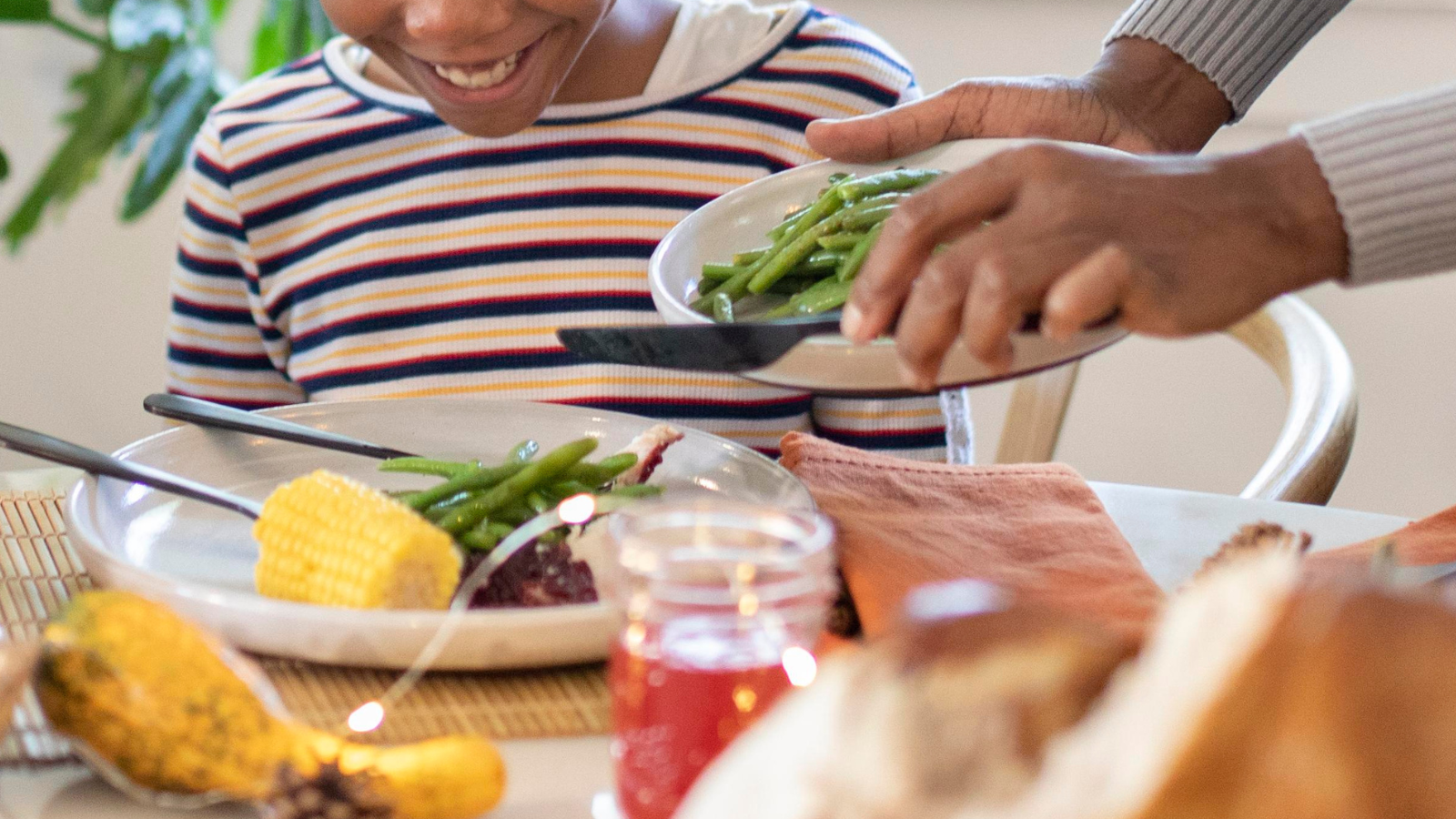 Parent serving vegetables onto a child’s plate during a calm mealtime, representing paediatric feeding support and family mealtime routines.