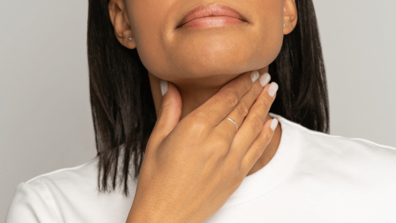 Adult touching the front of their throat, representing swallowing changes and dysphagia concerns.