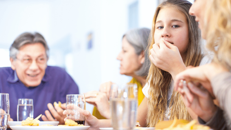 Teens sitting together at a table sharing a relaxed mealtime.