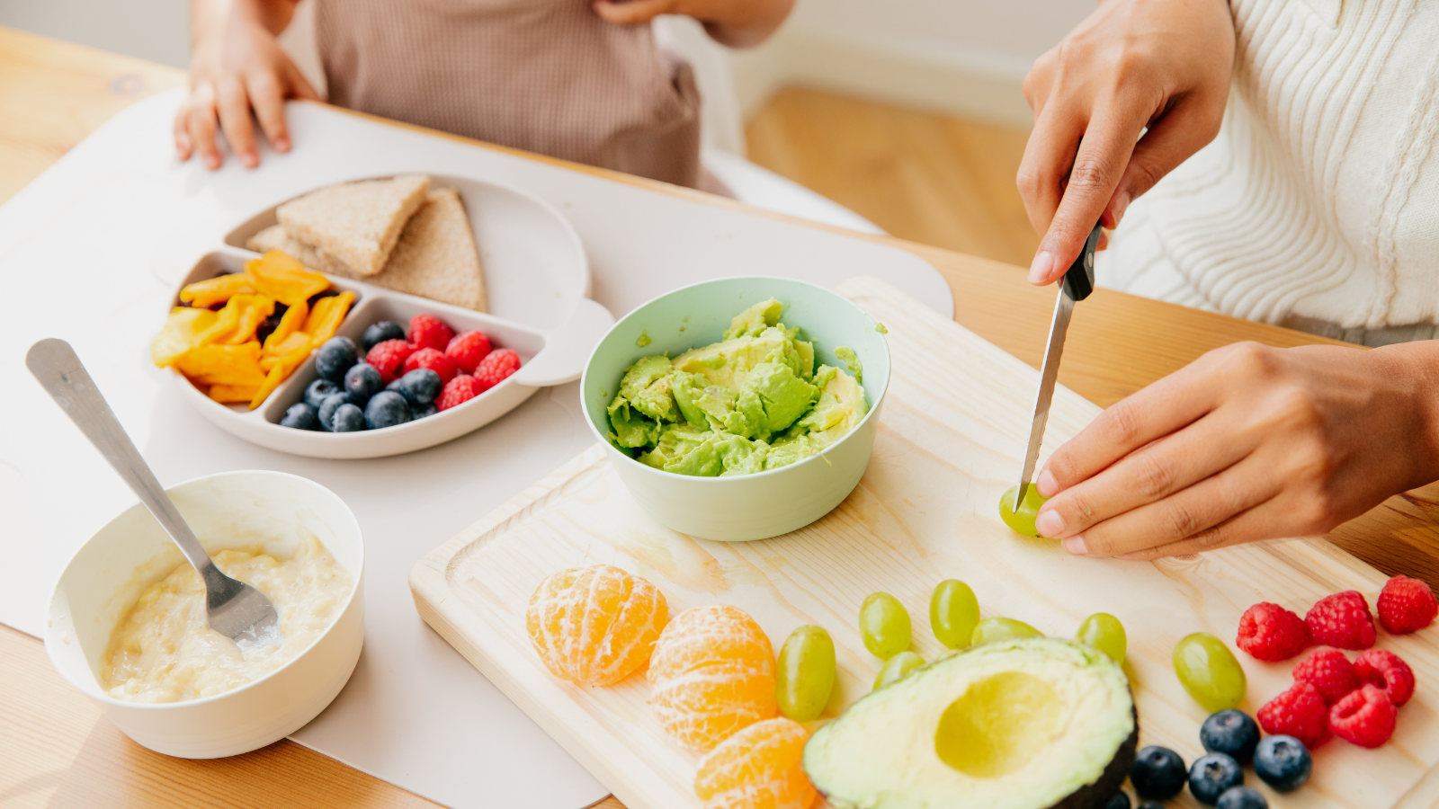 Fresh fruit and finger foods being prepared on a wooden board, representing feeding support and mealtime development across the lifespan.