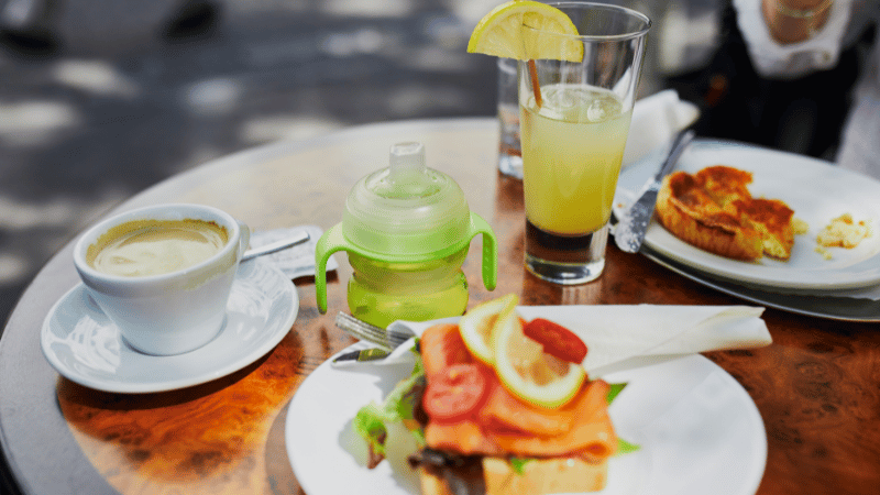 A tall glass of juice, a sippy cup and a coffee cup on a table, symbolising swallowing support across children, adults and older adults.